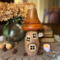 A mushroom fairy house made from dried gourds. It has an orange roof, carved windows, a Rabbit Chateau House sign hangs off the side.